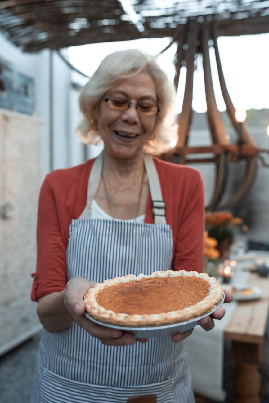 smiling elderly woman carrying a pumpkin pie