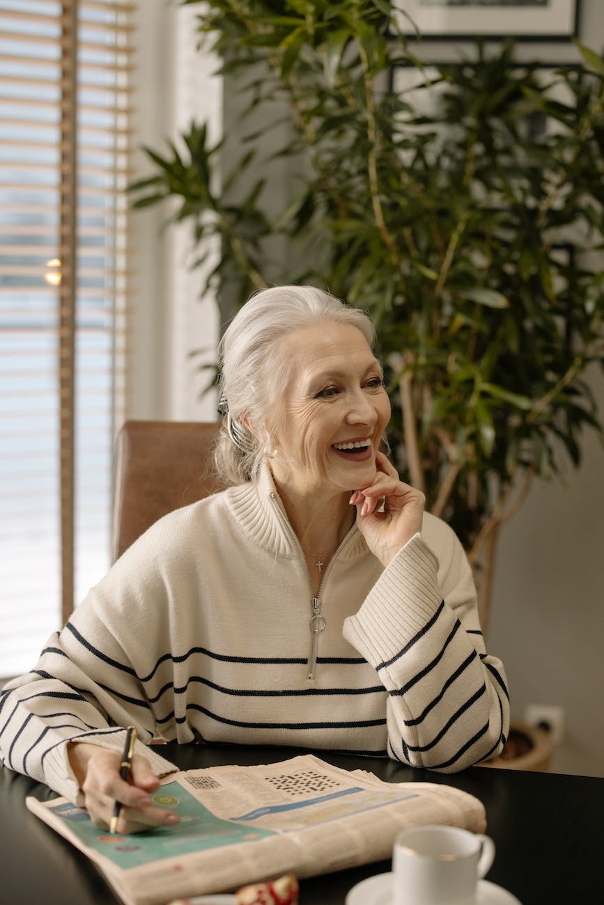 an elderly woman smiling while doing a puzzle