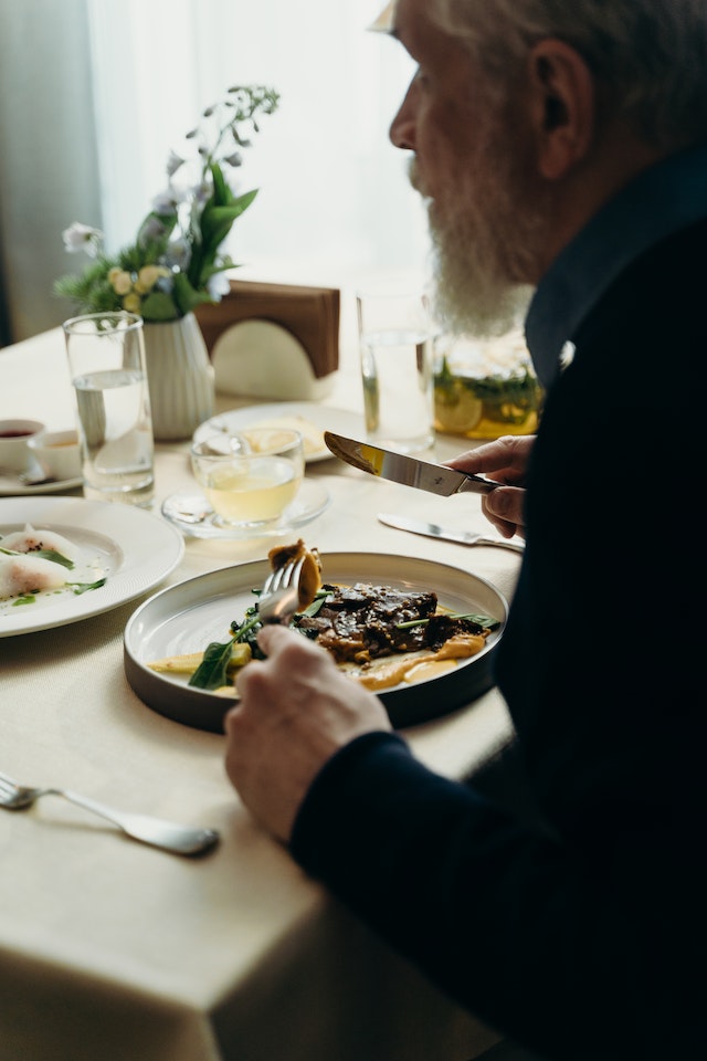 elderly man eating steak