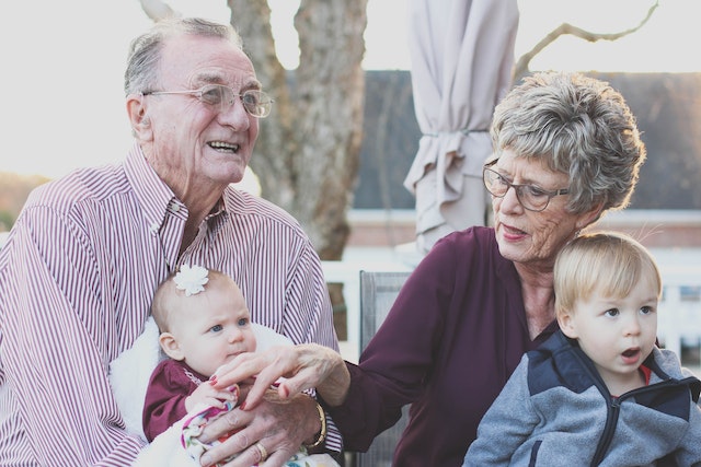 an elderly couple holding their grandchildren